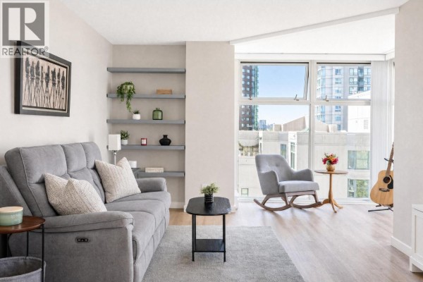 Living room with gray sofa, rocking chair, and a guitar, large windows offer city views. - B901 1331 Homer Street, Vancouver