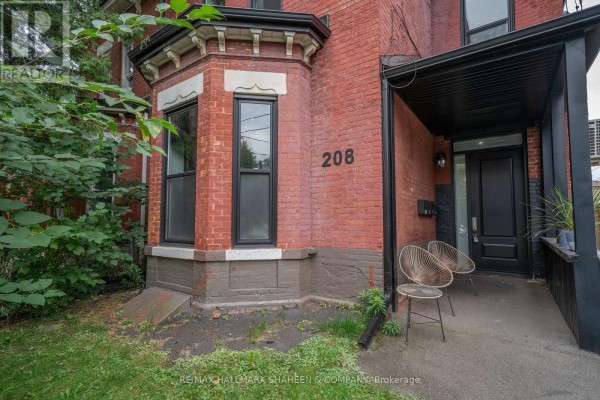 Close-up of the house entrance with number 208, a bay window, and outdoor chairs. - Bachelor - 208 Dovercourt Road, Toronto