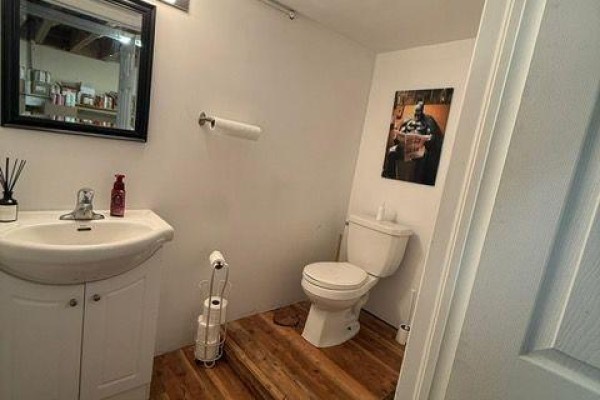 Small bathroom with a sink, toilet, and a mirror above the sink. - Back - 15 Dunlop Street W, Barrie