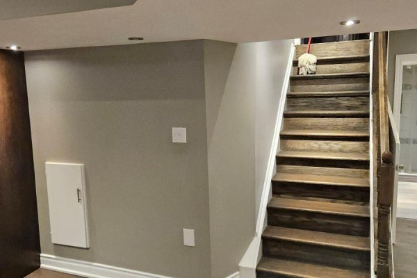 Wooden staircase with dark treads and a mop at the top, leading to the main floor. - Basement - 118 Earlsbridge Boulevard, Brampton