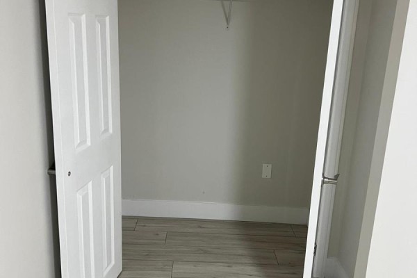 Empty walk-in closet with white doors, white baseboards, and light wood-look flooring. - Basement - 12467 Kennedy Road N, Caledon