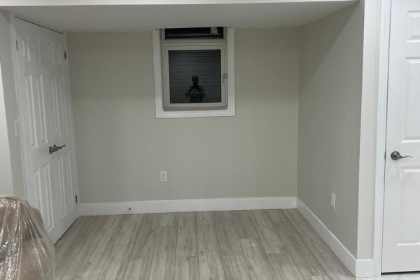Empty room with a small window, white doors, white baseboards, and light wood-look flooring. - Basement - 12467 Kennedy Road N, Caledon