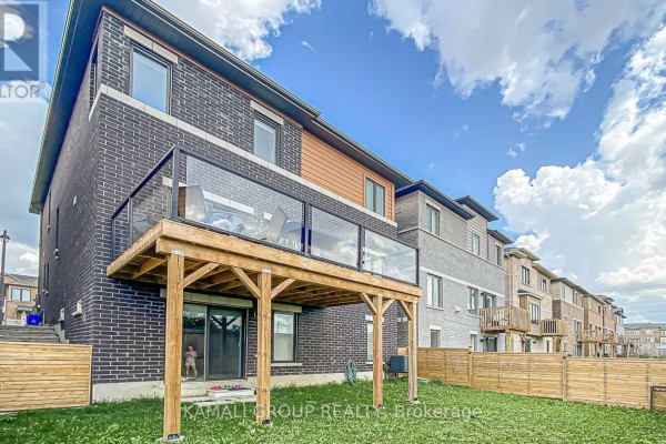 Rear exterior of house with wooden deck, glass railing, and fenced backyard. - Basement - 130 Vantage Loop, Newmarket