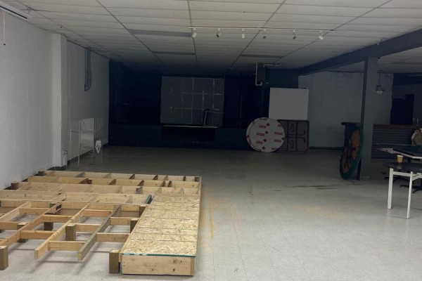 Unfinished commercial basement with wood subflooring, tables, and dark walls in the background. - Basement - 1472 Dundas Street, London East