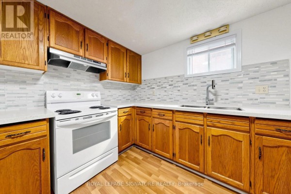 Basement kitchen with light wood cabinets, white countertops, white stove, and a mosaic tile backsplash. - Basement - 156 Centennial Road, Toronto