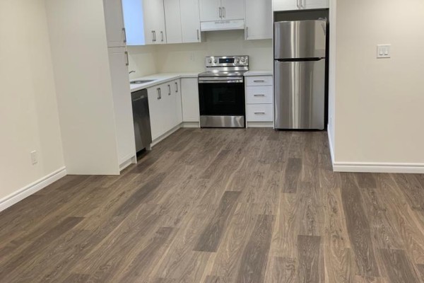 Open kitchen area with stainless steel appliances, white cabinets, and laminate flooring. - Basement - 18 Elderslie Crescent, Vaughan