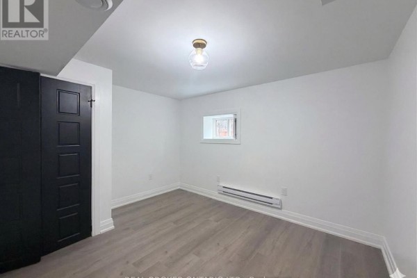 Empty room with a window, black closet doors, and overhead light fixture. - Basement - 184 Ottawa Street S, Hamilton