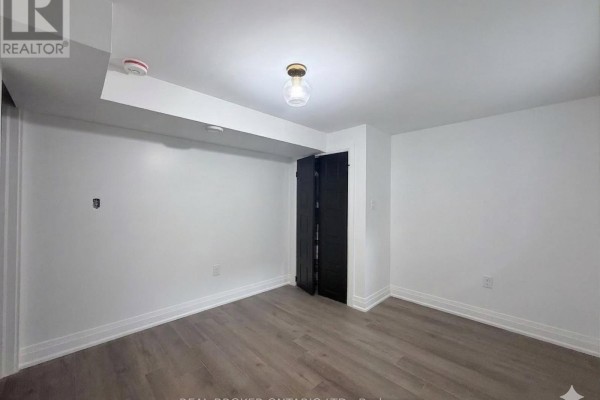 Another empty room with black closet doors and a light fixture, minimal decor. - Basement - 184 Ottawa Street S, Hamilton