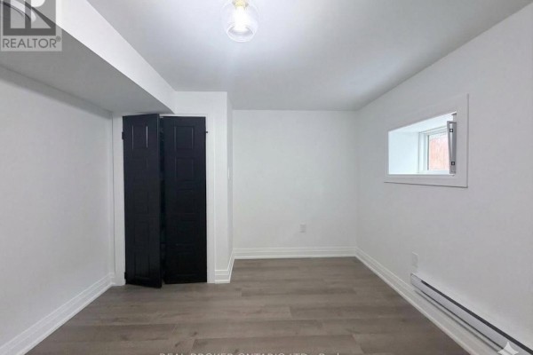 Bright room with a window, black closet doors, and neutral walls and flooring. - Basement - 184 Ottawa Street S, Hamilton
