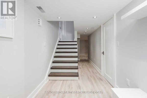 Basement hallway with light wood-look flooring and a staircase leading up. - Basement - 187 Brooke Avenue, Toronto