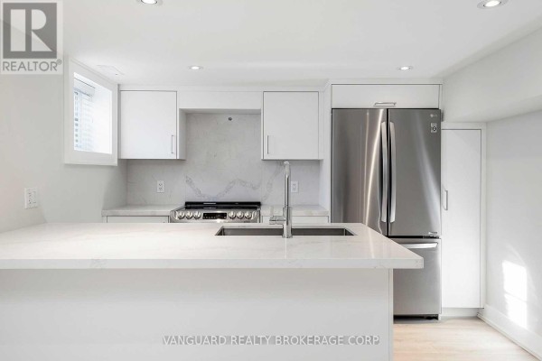 Close-up of a modern basement kitchen island with a double sink and faucet. - Basement - 187 Brooke Avenue, Toronto