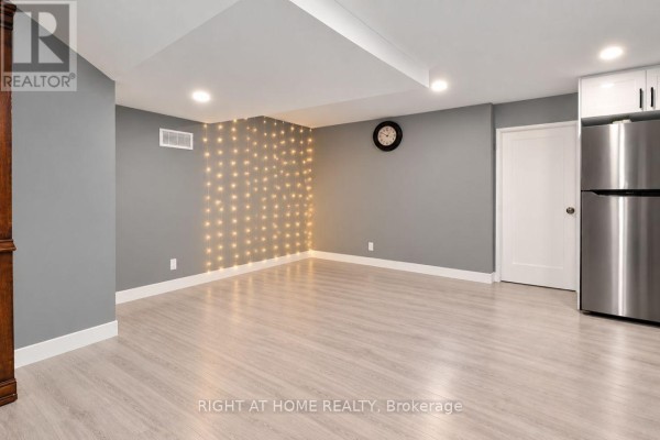 Finished basement living area with grey walls, wood-look flooring, and decorative lights. - Basement - 200 Renfro Crescent, London South