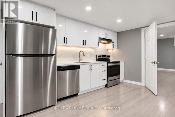 Basement kitchen with white cabinets, stainless steel appliances, and light wood-look flooring. - Basement - 200 Renfro Crescent, London South