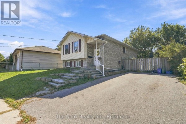 Side view of the house showing a paved driveway and fenced backyard. - Basement - 255 Greenwood Avenue, Oshawa