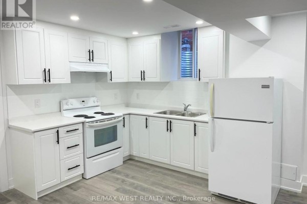 Another view of the basement kitchen showing white cabinets, white countertop, white appliances, and window. - Basement - 26 Smoothwater Street, Brampton