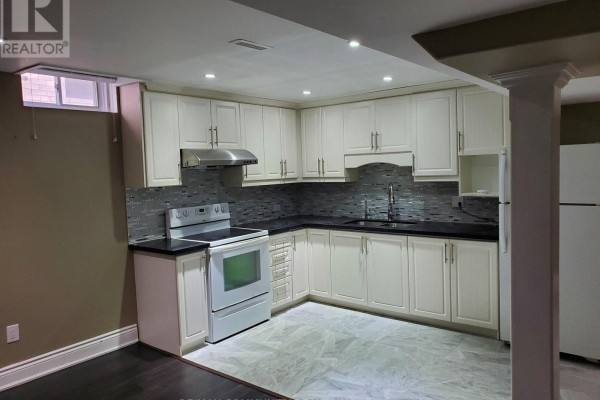 Basement kitchen with white cabinets, black countertops, stainless steel appliances, and tiled backsplash. - Basement - 27 Karen Miles Crescent, Markham