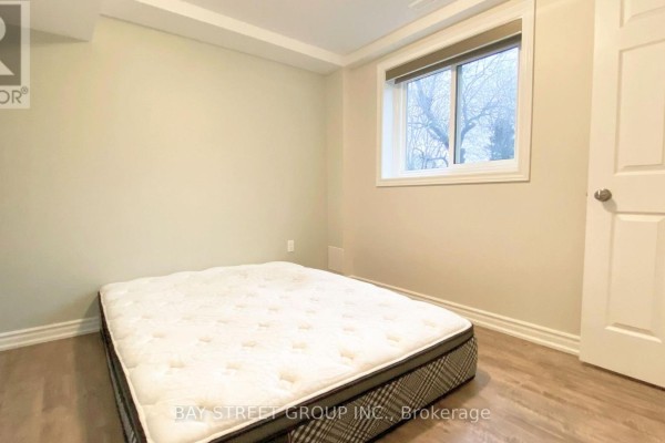 Basement bedroom with a mattress on the floor, beige walls, and a window with blinds. - Basement - 29 Carlton Road, Markham