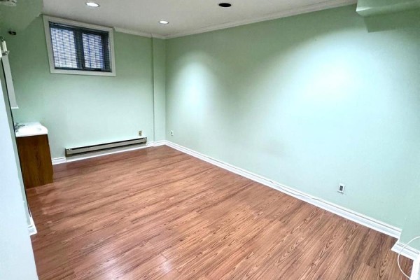 Empty basement room with light green walls, a window with blinds, and wood laminate flooring. - Basement - 3 Blairville Road, Toronto