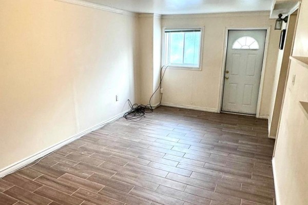 Basement room with light beige walls, a window, a white door, and wood-look tile flooring. - Basement - 3 Blairville Road, Toronto