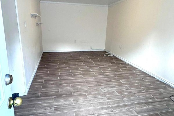 Empty basement room with light beige walls and wood-look tile flooring, viewed from the doorway. - Basement - 3 Blairville Road, Toronto