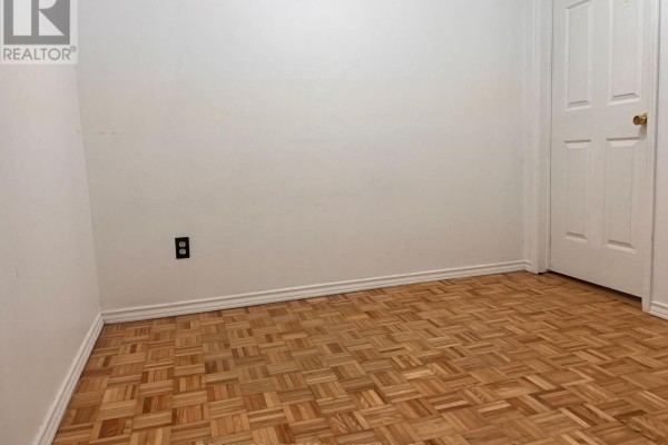 Empty basement room with white walls, a white door, and a parquet wood floor. - Basement - 3156 Mccarron Crescent, Mississauga