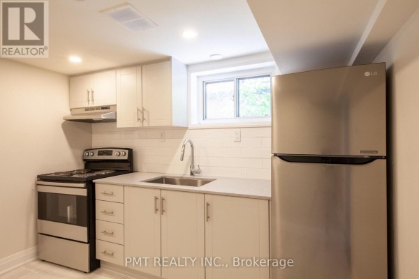 Compact basement kitchen with white cabinets, stainless steel appliances, and a subway tile backsplash. - Basement - 34 Robindale Avenue, Toronto