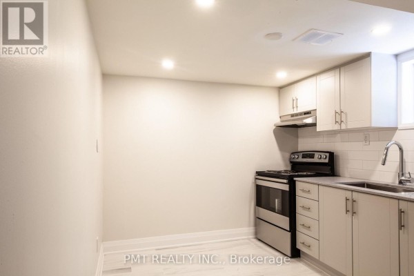 Basement kitchen featuring light grey cabinets, a stainless steel stove, and white subway tile backsplash. - Basement - 34 Robindale Avenue, Toronto