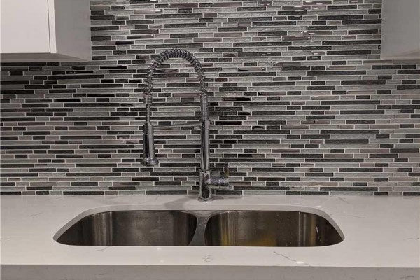 Close-up of a double stainless steel sink and pull-down faucet against a mosaic backsplash. - Basement - 39 Wood Rim Drive, Richmond Hill