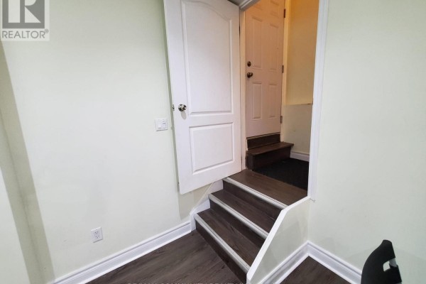 Interior basement entrance with white door, dark wood steps, and pale green walls. - Basement - 4 Elliottglen Drive, Ajax