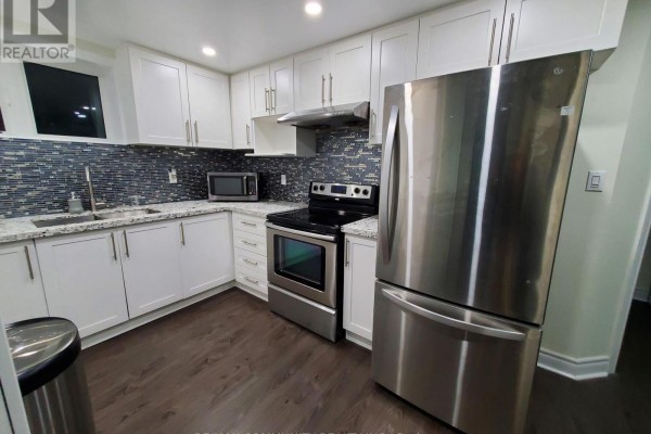 Modern basement kitchen with white cabinets, stainless steel appliances, and mosaic tile backsplash. - Basement - 4 Elliottglen Drive, Ajax