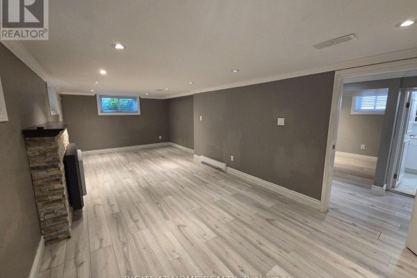 View of the spacious basement living area from the side, showing windows and a doorway to another room. - Basement - 46 Haverson Boulevard, Toronto