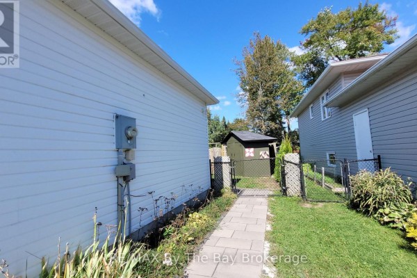 Pathway leading between white vinyl siding and fence to a green shed in the backyard. - Basement - 48 Caribou Trail, Wasaga Beach