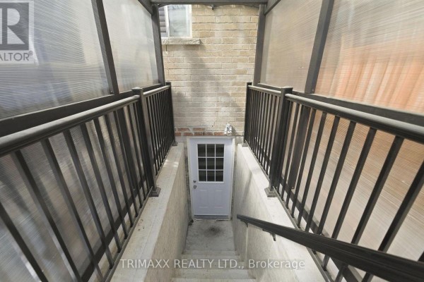 Concrete stairs with black metal railings leading down to a basement door. - Basement - 5 Watson Drive, New Tecumseth