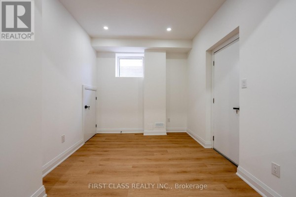 Empty basement room with white walls, laminate flooring, a small window, and two interior doors. - Basement - 544 White's Hill Avenue, Markham