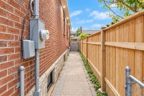 Narrow paved walkway between a brick house and a wooden privacy fence. - Basement - 6 Azrock Road, Toronto