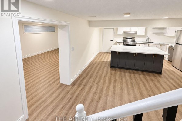 Open concept basement living area with a kitchen island and light wood laminate flooring. - Basement - 6 Azrock Road, Toronto