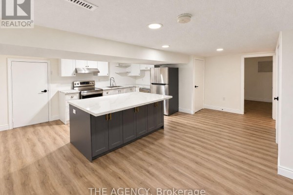 Basement kitchen with white cabinets, stainless steel appliances, and a large island. - Basement - 6 Azrock Road, Toronto