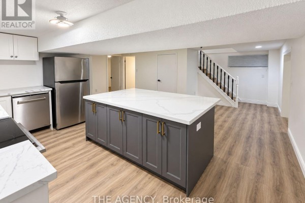 Basement kitchen with stainless steel refrigerator, large island, and view of stairs. - Basement - 6 Azrock Road, Toronto