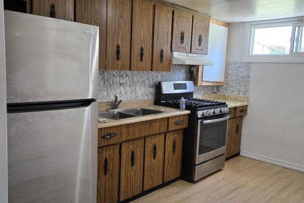 Small kitchen with wood cabinets, stainless steel refrigerator, double sink, and gas stove. - Basement - 61 Hardwick Court, Toronto