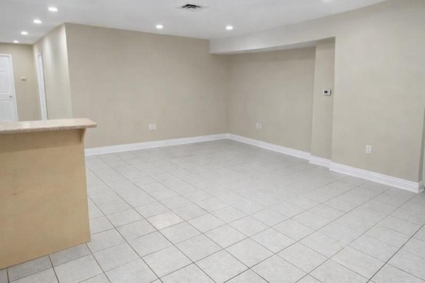 Empty room with beige walls, white baseboards, and light beige square tile flooring. - Basement - 621 Dixon Road, Toronto