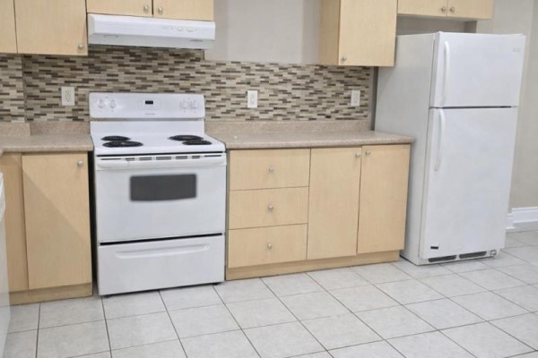 Kitchen area with light wood cabinets, white stove, beige countertop, and tiled backsplash. - Basement - 621 Dixon Road, Toronto