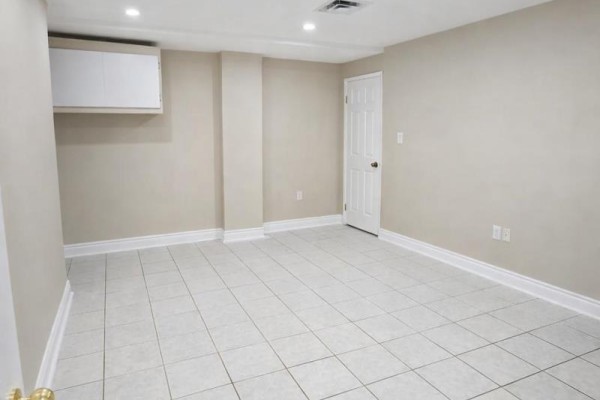 Interior view of a room with beige walls, white trim, and light beige square tiles. - Basement - 621 Dixon Road, Toronto