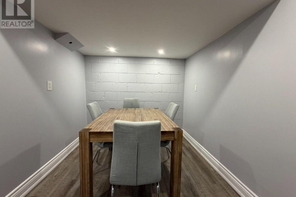 Dining area with a wooden table and four grey upholstered chairs. - Basement - 65 Glen Agar Drive, Toronto
