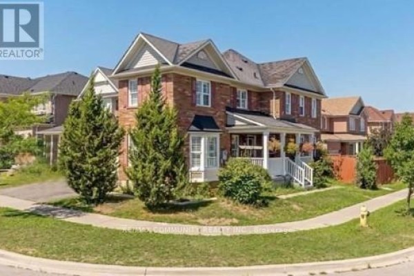 Side view of a brick house with a sloping lawn and trees. - Basement - 68 Hyacinth Crescent, Toronto