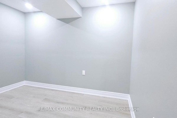 Empty room with light gray walls, white trim, and light wood laminate flooring. - Basement - 68 Hyacinth Crescent, Toronto
