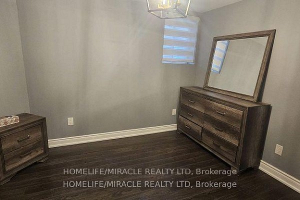 Basement bedroom with dark wood laminate flooring, grey walls, and dark wood furniture. - Basement - 718 Speyer Circle, Milton