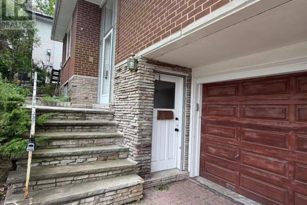 Basement kitchen with white and brown cabinets, appliances, a black faucet, and a sliding glass door to a patio. - Basement - 74 Valentine Drive, Toronto