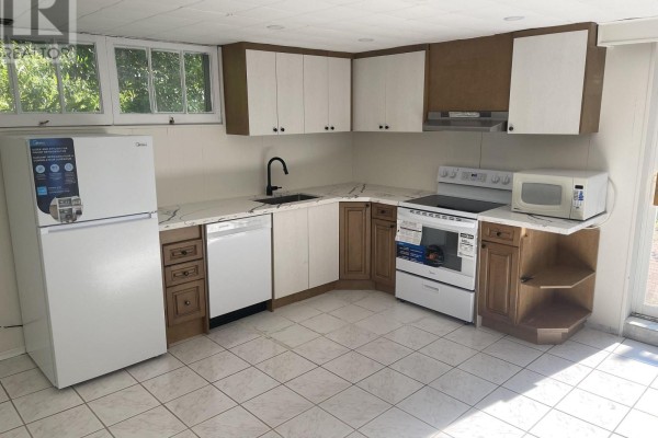 View of the basement kitchen area and a sliding glass door leading to a brick patio. - Basement - 74 Valentine Drive, Toronto