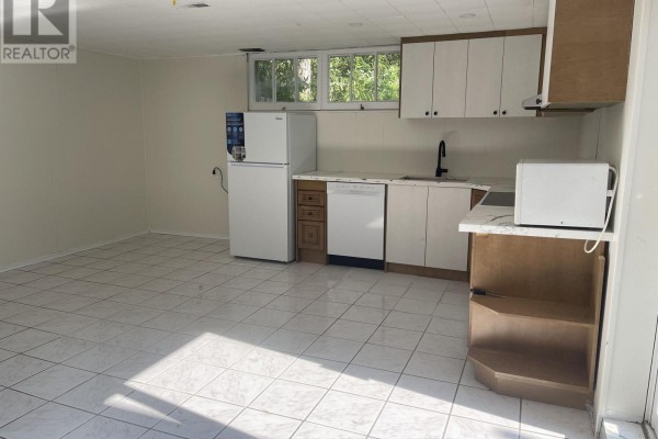 Basement kitchen with white tiled floor, white and brown cabinets, refrigerator, dishwasher, stove, and microwave. - Basement - 74 Valentine Drive, Toronto