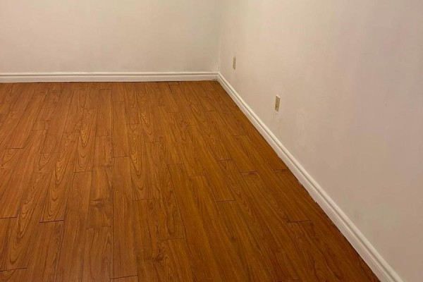 Empty room with wood laminate flooring and white walls with white baseboards. - Basement - 75 Windrush Trail, Toronto